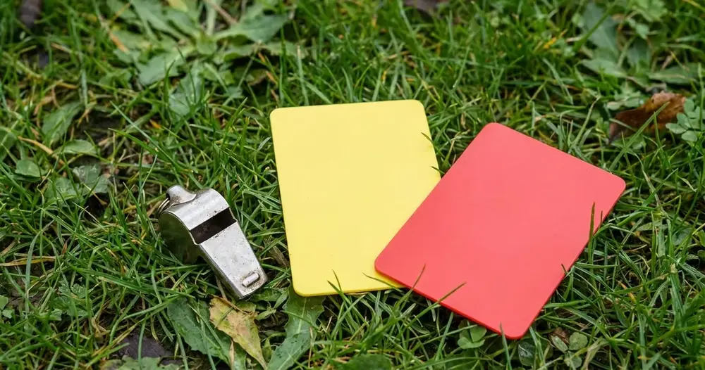 apito de árbitro com cartões amarelo e vermelho na grama